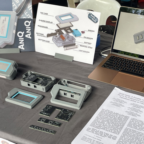 Exploded parts display of the handheld device with labeled printed case components and a laptop