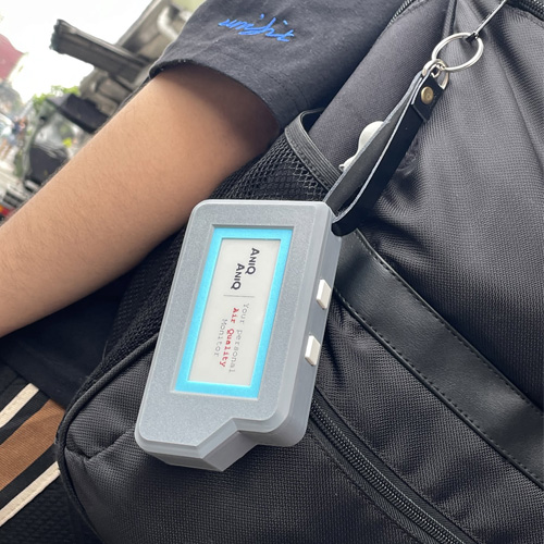 Handheld air quality device hanging on a lanyard from a bag