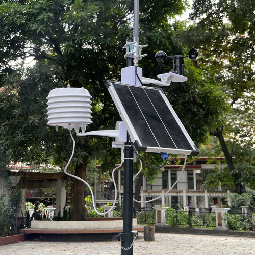 Outdoor air quality node on a mast with a louvered sensor housing, solar panel, and wind sensor