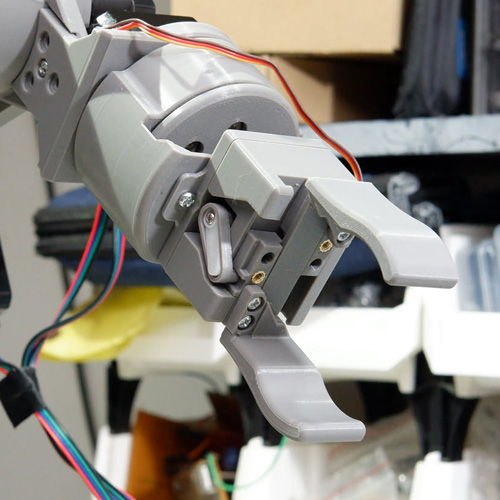 Close-up of the printed two-finger gripper and wiring at the end of the robot arm